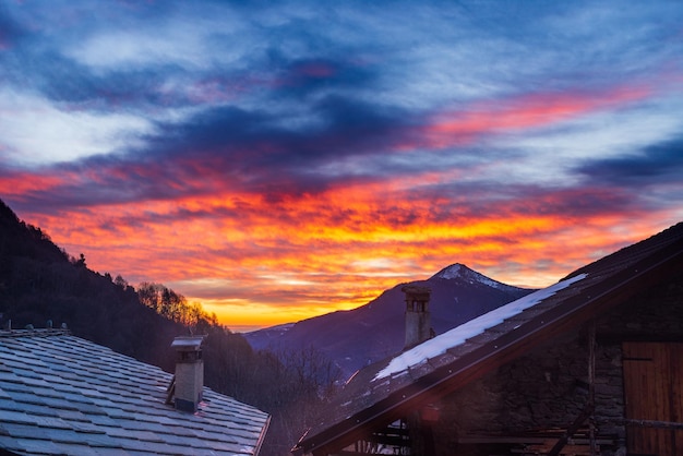 Gloriosa puesta de sol en los Alpes italianos Hermoso cielo sobre valle nevado idílico pueblo y picos nevados Invierno en Piamonte Italia