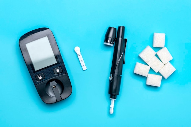 Foto glucometer-zuckerwürfel auf blauem hintergrund konzept für hohen blutzucker und diabetes