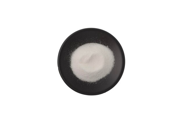 Gluconolactona delta (GDL), también conocida como glucolactona, aditivo alimentario E575 en un plato negro sobre blanco.