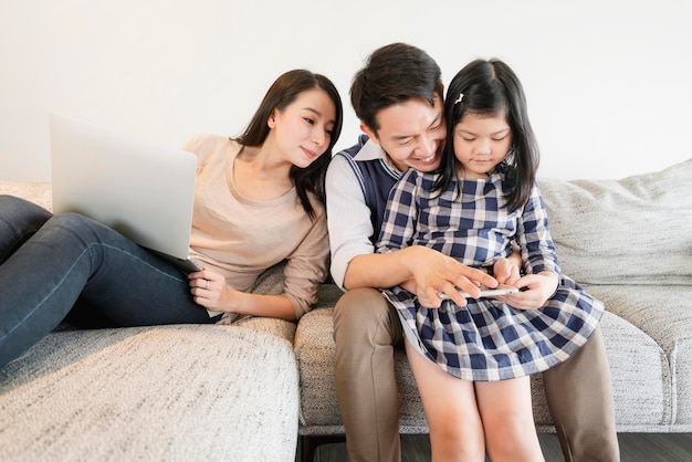 Glück asiatischer familienwochenende urlaub mit mama papa tochter bleiben zusammen mit tablet und laptop hausinnenhintergrund