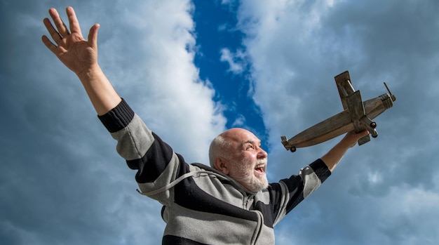 Glück eines älteren Mannes im Ruhestand Reifer Mann im Ruhestand Alter Mann auf Himmelshintergrund mit Spielzeugflugzeug