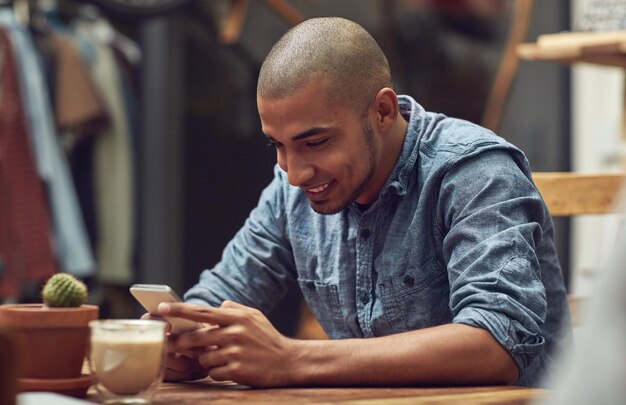 Glück ist nur einen Fingertipp entfernt Aufnahme eines jungen Mannes, der sein Telefon in einem Café benutzt