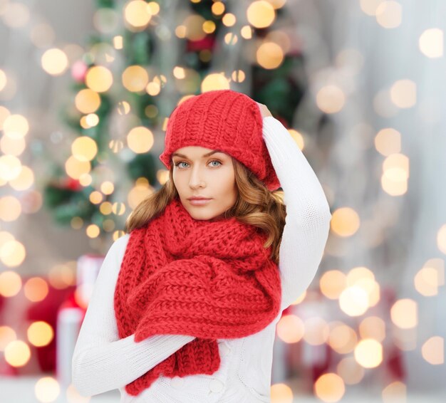 Glück, Winterferien und Personenkonzept - junge Frau mit rotem Hut und Schal über Weihnachtsbaum beleuchtet Hintergrund