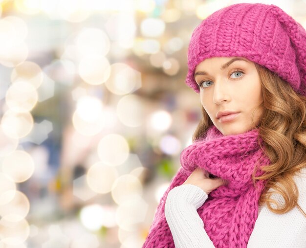 glück, winterferien, weihnachten und personenkonzept - junge frau in rosa mütze und schal über lichthintergrund