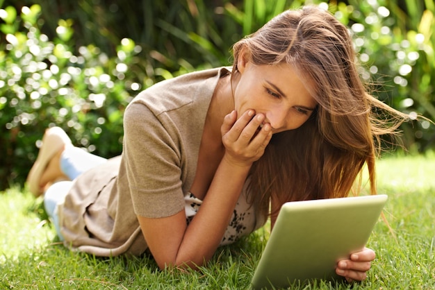 Glück, wo sich Technologie und Natur treffen Aufnahme einer Frau, die es genießt, ihr digitales Tablet im Freien zu verwenden
