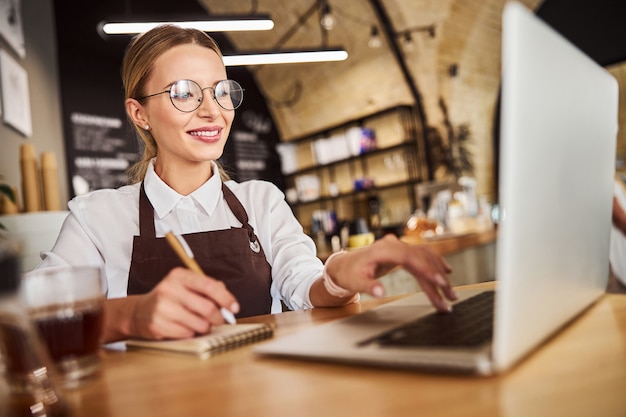 Glücklich lächelnde Dame in Uniform mit Laptop im Job