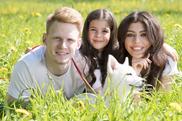 Foto glücklich lächelnde familie von eltern und tochter mit hund im park