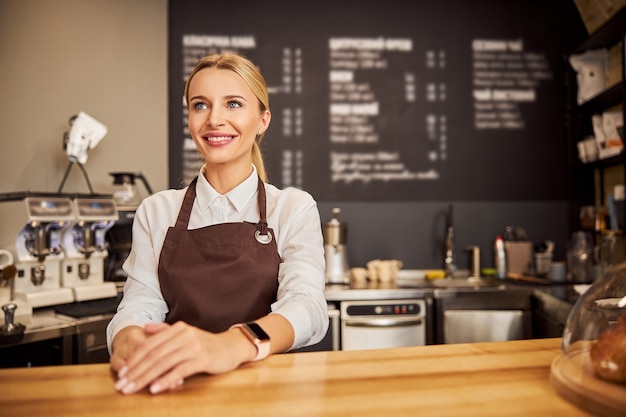 Glücklich lächelnde Kellnerin, die an der Fotokamera im Café posiert?