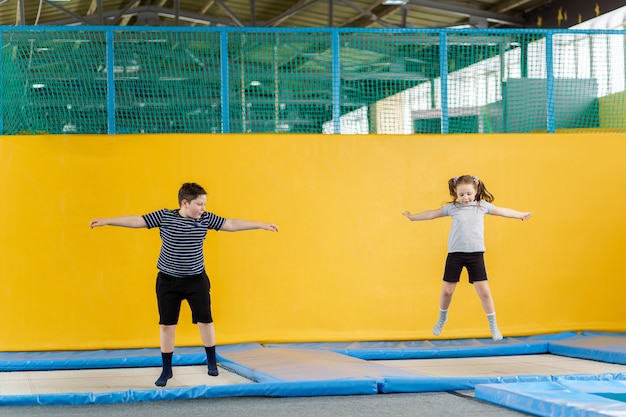 Glücklich lächelnde kleine Kinder, die auf Innen Trampolin im Unterhaltungszentrum springen