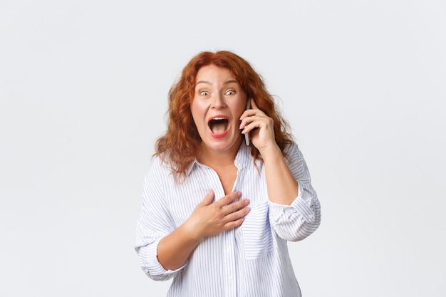 glücklich lächelnde rothaarige Frau fand erstaunliche Nachrichten über Handy heraus