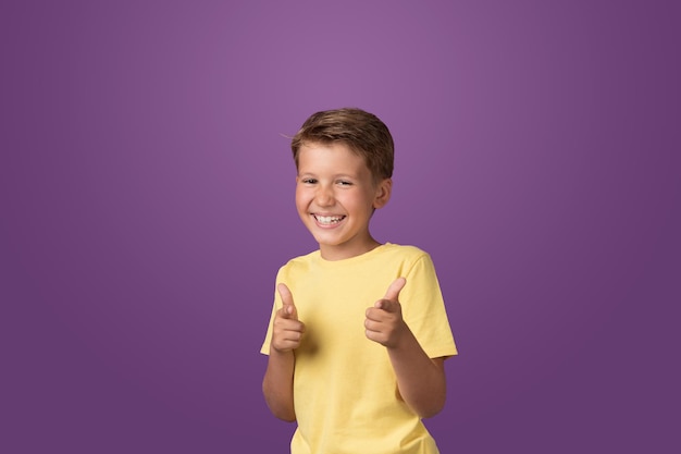 Glücklich lächelnder kaukasischer jugendlicher Junge, der vor lila Hintergrund in die Kamera schaut