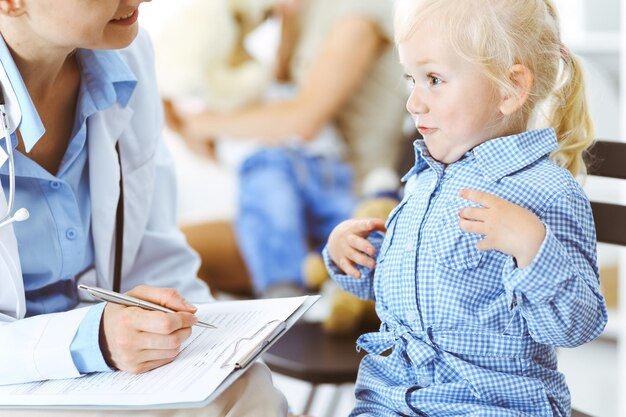 Foto glücklich lächelnder kinderpatient bei der üblichen ärztlichen untersuchung. arzt und patient in der klinik. medizin, gesundheitskonzepte.