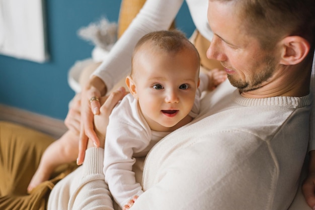 Glücklich lächelndes Baby in den Armen des Vaters im Haus