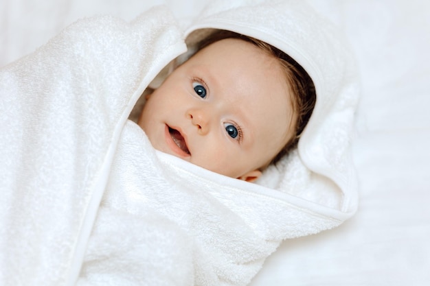 Glücklich lächelndes Baby in einem Handtuch nach dem Baden eines glücklichen Kinderporträts
