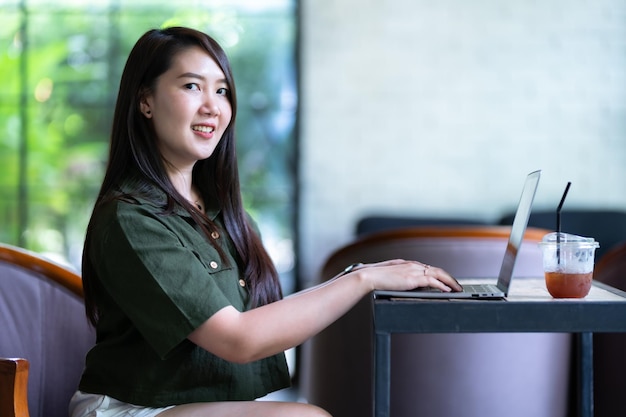 Glücklich von asiatischen freiberuflichen geschäftsfrauen, die lässig mit laptop-computer mit kaffeetasse und smartphone im café arbeiten, mögen das hintergrundkommunikationskonzept