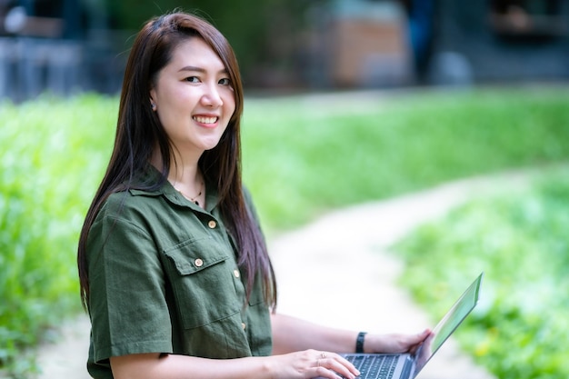 Glücklich von asiatischen freiberuflichen geschäftsfrauen, die mit laptop-computer im freien an einem sonnigen sommertag im parkhintergrund arbeiten. bildungs- und fernarbeitskommunikationskonzept