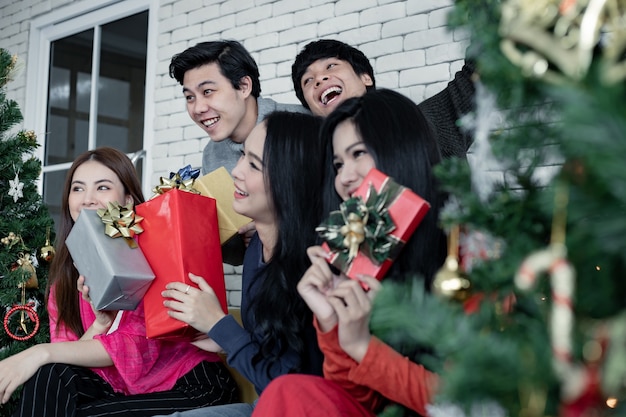Glücklich von der Gruppe junger Asiaten mit Geschenken zu Hause beim Feiern des Weihnachtsfestes. Gruppe von Freunden, die sich zusammen für die Weihnachtsfeier verkleiden. Feiern des neuen Jahres. Frohe Weihnachten und schöne Feiertage.