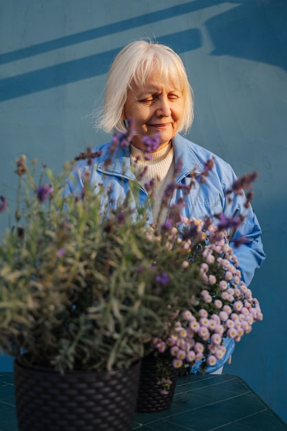 Glückliche ältere Frau, die mit Blumen im Garten arbeitet. Positives weibliches Lächeln im Ruhestand