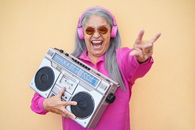 Glückliche ältere Frau, die Rockmusik mit Boombox Vintage Stereo hört