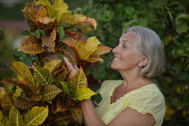 Glückliche ältere Frau im tropischen Garten im Freien