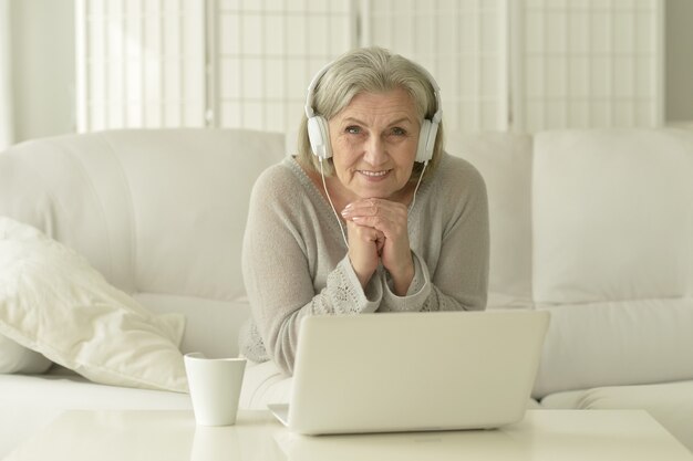 glückliche ältere Frau mit Laptop und Kaffee zu Hause