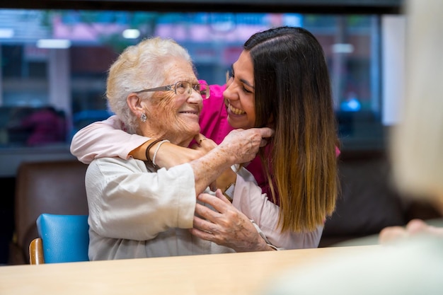 Glückliche ältere Frau und Krankenschwester umarmen sich in einer Geriatrie