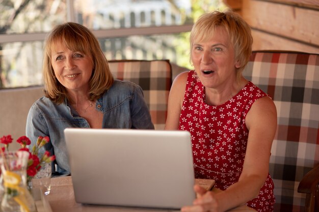 Glückliche ältere Frauen, die Laptop halten und zu Hause zusammen arbeiten