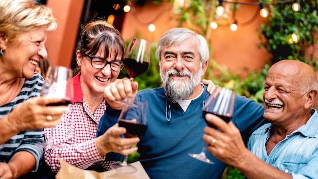 Glückliche ältere Freunde, die Spaß haben, Rotwein auf der Dinnerparty zu rösten - Konzentrieren Sie sich auf bärtigen Mann