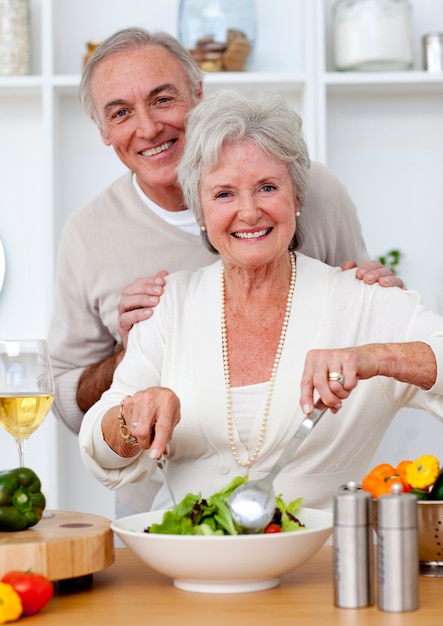 Glückliche ältere Paare, die einen Salat in der Küche eeating sind