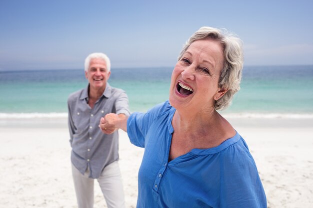 Glückliche ältere Paare, die Hand auf dem Strand halten