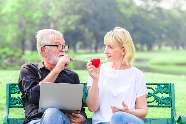 Glückliche ältere Paare im Park, der Herz im Liebesvalentinstagkonzept hält