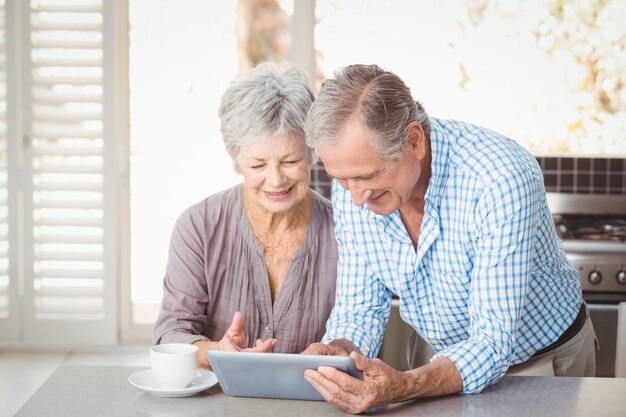 Glückliche ältere Paare unter Verwendung der Tablette