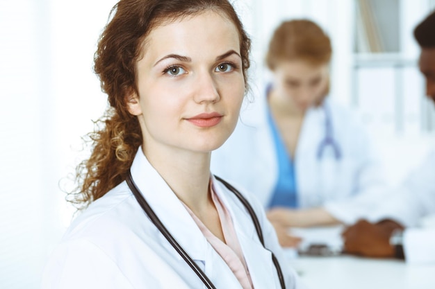 Foto glückliche ärztin mit medizinischem personal im krankenhaus. multiethnische volksgruppe.