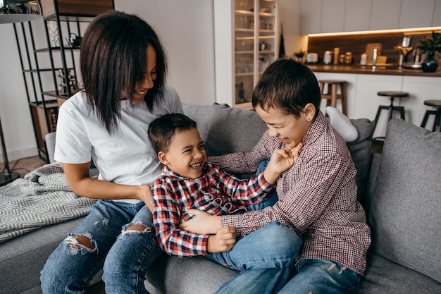 Glückliche afroamerikanische Familienmutter und zwei Söhne, die herumalbern und Spaß zu Hause zusammen haben. Hochwertiges Foto