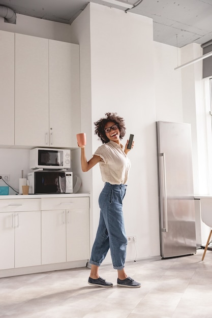 Glückliche afroamerikanische Frau, die Handy hält und Musik hört