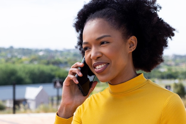 Glückliche afroamerikanische Geschäftsfrau, die geht und mit dem Smartphone spricht. Globales Geschäft, Finanzen, unterwegs und Bürokonzept.