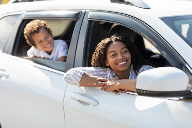 Glückliche afroamerikanische Mutter und Sohn schauen aus Autofenstern
