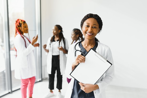 Glückliche afroamerikanische Ärztin oder Krankenschwester über Gruppe von Medizinern, die sich im Krankenhaus treffen