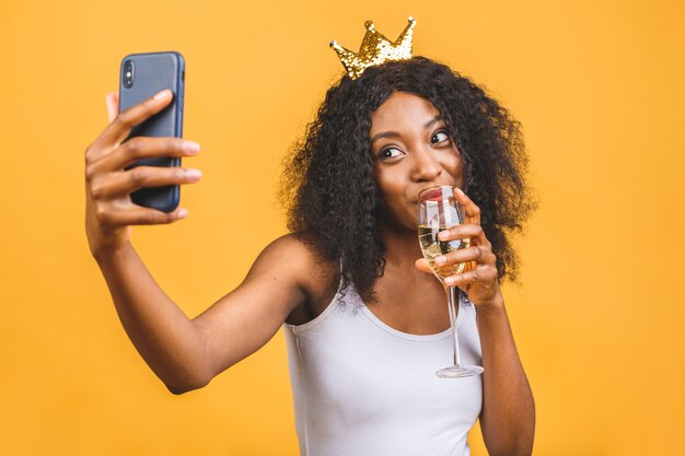 Glückliche afroamerikanische schwarze Frau mit Glas Champagner und goldener Krone