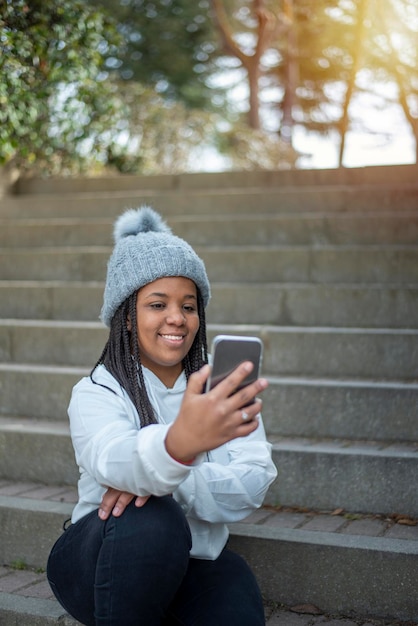 Glückliche Afrofrau, die Handy im Park verwendet