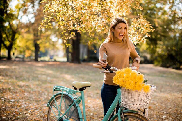 Glückliche aktive Frau, die im Herbstpark Fahrrad fährt