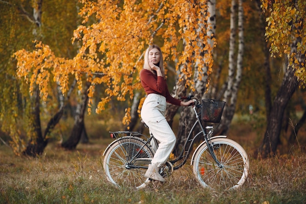 Glückliche aktive junge Frau, die Fahrrad im Herbstpark reitet.