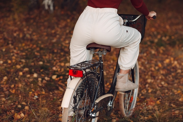 Glückliche aktive junge Frau, die Fahrrad im Herbstpark reitet.