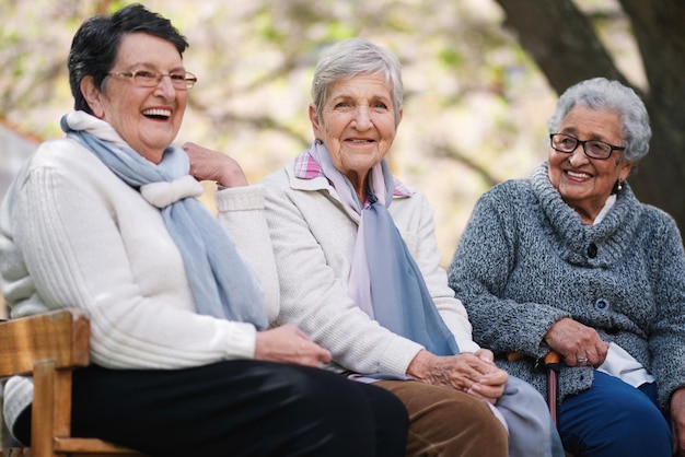 Glückliche alte Frauen, die auf einer Bank im Park sitzen, lächeln glückliche lebenslange Freunde, die gemeinsam den Ruhestand genießen