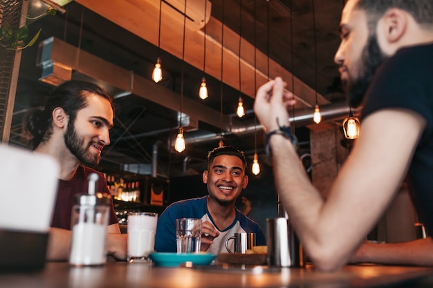 Glückliche arabische junge Männer, die im Loft-Café hängen
