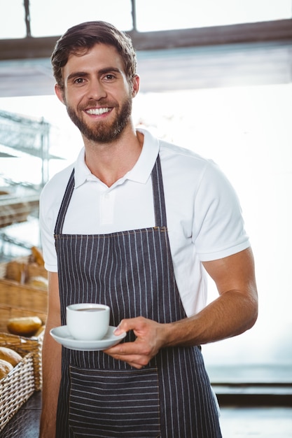 glückliche Arbeitskraft im Schutzblech, das einen Tasse Kaffee hält