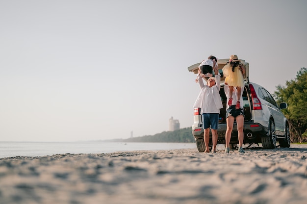 Glückliche asiatische Familie, die einen Strandausflug mit ihrem Lieblingsauto genießt Eltern und Kinder reisen