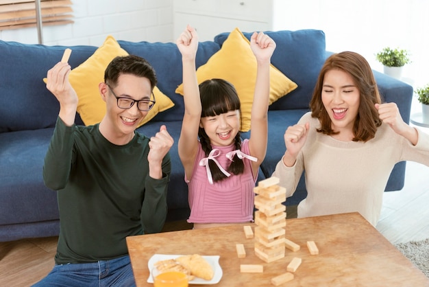 Glückliche asiatische Familie, die Spaß hat, Jenga-Spiel im Wohnzimmer zu Hause zu spielen.