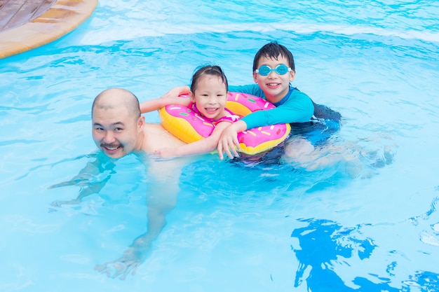 Glückliche asiatische Familie, die zusammen im Swimmingpool spielt