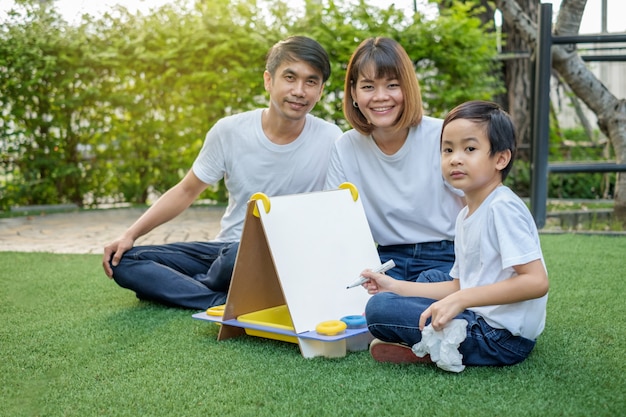 Glückliche asiatische Familie im Hinterhof auf dem Gras